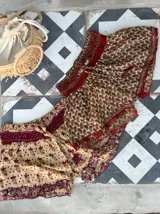 Short de seda con elástico fruncido en la cintura y volado en el ruedo. Presenta un estampado vibrante en tonos rojo/bordó y turquesa con motivos florales o arabescos.