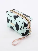 Neceser rectangular con estampado de manchas de vaca en tonos rosa y negro, cierre superior con cremallera dorada y correa de muñeca extraíble.