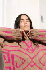 Sweater de lana color beige con jacquard geométrico en color fucsia. Tiene corte oversize, mangas largas y cuello redondo.