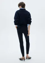 Pantalón negro de corte skinny, tiro medio y largo a la altura del tobillo.