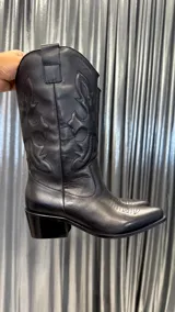 Bota texana de cuero negro con bordados en el caño y taco bajo.