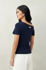 Top tejido azul marino de silueta ajustada con diseño minimalista y escote asimétrico, adornado con pequeños botones metálicos.