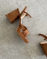 Sandalia de cuero vacuno color dorado, con plataforma y taco cuadrado. Presenta una tira delgada en el tobillo y detalle de nudo en la capellada.