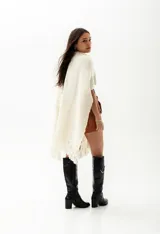 Ruana color crudo de tejido de punto grueso con flecos.