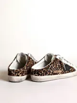 Zapatilla Golden Goose modelo Super-Star, sin talón, con estampado animal print de leopardo, estrella negra de cuero en el lateral y cordones grises.