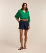 Short clochard azul marino de viscolino con trabillas en la cintura, cinturón con hebilla de madera y pliegues.