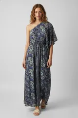 Vestido largo de poliéster con estampado paisley en tonos azul, lila y verde. Tiene un hombro descubierto, manga abullonada, cintura elastizada y volados en el ruedo.