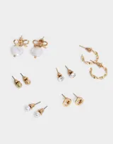 Set de seis pares de aros dorados con distintos diseños: aros tipo botón con perla, aros tipo botón con strass, aros tipo botón dorados, aros de argolla y aros colgantes con dije de perla y moño.
