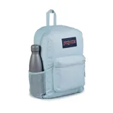 Mochila JanSport celeste con logo rectangular en azul marino y rojo. Tiene un compartimento principal grande, un bolsillo lateral para botella de agua, un bolsillo frontal con cremallera, tirantes acolchados y panel trasero acolchado.