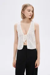 Top sin mangas de algodón color blanco, tejido al crochet, con escote en V profundo y lazo de ajuste en el frente.