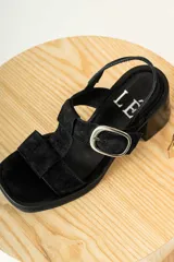 Sandalias negras de charol con tiras entrecruzadas, hebilla dorada y tacón de madera.