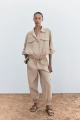 Pantalón de tiro medio color beige, con cintura elástica ajustable con cordones, bolsillos delanteros y puños elásticos en los tobillos.