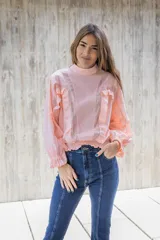 Blusa lila de cuello alto y manga 3/4 con elástico en el bajo. Presenta volados verticales en el frente.