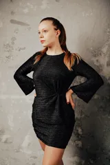 Vestido negro de punto con brillo, corte ajustado y mangas largas acampanadas.