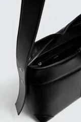 Bolso tipo shopper color negro, con asa de hombro y compartimento principal con cierre de cremallera. El interior cuenta con un bolsillo plano y un bolsillo con cierre de cremallera.