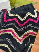 Buzo negro de manga larga con detalles de lentejuelas bordadas en forma de zigzag en colores oro, fucsia y marrón.