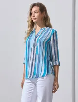 Blusa de gasa estampada con rayas verticales en tonos celeste, azul y blanco. Tiene cuello a la base con escote en V y abertura con botones. Las mangas largas son de largo regulable.