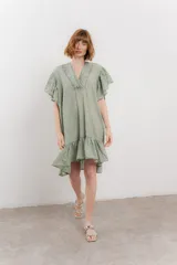 Vestido corto color verde oliva, confeccionado en algodón. Presenta escote en V con detalles bordados, mangas amplias con volados y falda con ruedo en volado.