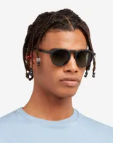 Lentes de sol Hawkers unisex, modelo Warwick Raw, con montura redonda color negro mate y lentes polarizadas color gris oscuro. Fabricados en España.