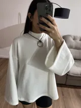 Sweater blanco de tela Aspen, cuello alto y mangas largas con puños acampanados.