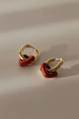 Aros tipo argolla de acero quirúrgico color dorado, con un dije colgante en forma de corazón de cerámica blanca.