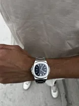 Reloj de pulsera Patek Philippe Nautilus con caja y brazalete de acero inoxidable, esfera azul con patrón horizontal en relieve y movimiento automático.