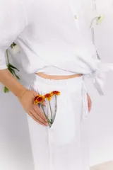 Pantalón blanco de lino con cintura elástica y cordón ajustable.