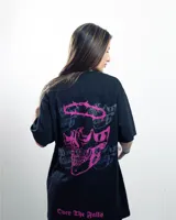 Remera negra de algodón con cuello redondo y mangas cortas. Presenta un estampado pequeño en el pecho con un diseño abstracto en tonos rosa y celeste.