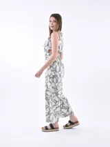 Monoprenda sin mangas con estampado orgánico en color verde y beige. Presenta un diseño con cuello redondo, aberturas laterales en la cintura con cordones ajustables y pantalones de pierna ancha.