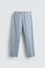 Pantalón de vestir celeste claro, corte slim fit, con bolsillos laterales y traseros de doble vivo con botón. Cierre frontal con cremallera y botón.