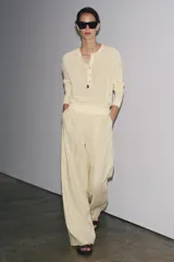 Jersey color crema de punto liso, con cuello redondo, tapeta de botones y manga larga.