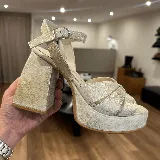 Sandalias de plataforma color dorado con tiras cruzadas en el empeine, pulsera con hebilla al tobillo y taco cuadrado alto.