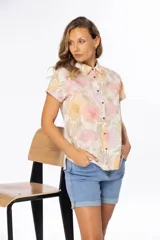 Camisa de manga corta con estampado floral en tonos pastel, cuello clásico y cierre frontal con botones.