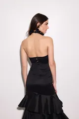 Falda larga negra de tafeta con cintura ajustada, tajo lateral y volados escalonados.