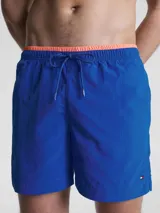 Bañador azul eléctrico de largo medio, con cintura elástica ajustable con cordón, ribete naranja en la cintura y logo de Tommy Hilfiger bordado en la parte trasera.
