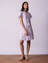 Vestido corto de lino a rayas verticales color lila y blanco, con cuello fruncido, escote en V y lazo de ajuste. Mangas cortas con puntilla de crochet.
