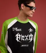 Remera de poliéster negra con mangas raglán verde lima y detalles blancos en los hombros. Presenta estampados con tipografías y gráficos en blanco en el frente.