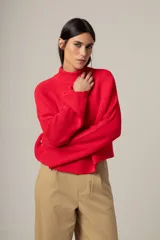 Sweater rojo de punto con cuello alto y mangas largas acampanadas.
