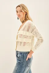 Cardigan color crema tejido en punto desagujado con volados tejidos en rib, calce crop y silueta ancha.