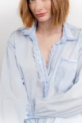 Camisa color crema de manga larga con cuello camisero y detalles de encaje en el escote. Se ata en la parte delantera.