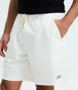 Bermuda de sarga lavada color verde claro, con lazo ajustable en la cintura, bolsillos laterales y un pequeño parche negro con logo en la pierna izquierda.