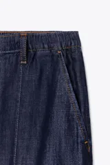Pantalón de jean azul oscuro, de tiro alto y pierna ancha, con cintura elástica ajustable con cordones y bolsillos delanteros.