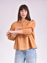 Blusa color beige con cuello mao, escote en V y mangas 3/4 con elástico en los puños.