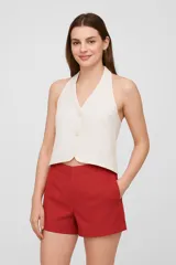 Chaleco corto blanco con bordado inglés, cuello halter y cierre frontal con botones.