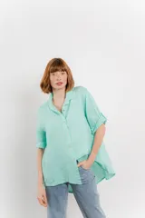 Camisa color verde agua, confeccionada en lino, de corte amplio, con cuello camisero, botones en el frente y mangas 3/4 que se pueden arremangar.