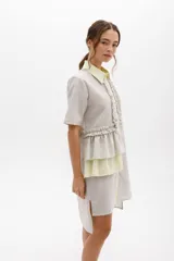 Vestido camisero a rayas con cuello y cartera en tono lima claro, volados frontales y laterales. De calce relajado y mangas cortas. Fabricado en Uruguay.