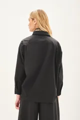 Camisa beige de poplin amplia, con botones laterales para abotonar de forma cruzada.