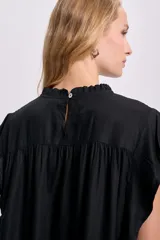 Blusa negra sin mangas con cuello redondo y detalle de volados en los hombros.