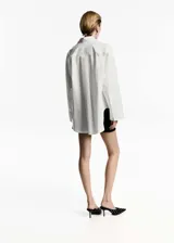 Camisa oversize blanca de popelina de algodón, con cuello camisero, manga larga con puños abotonados y cierre frontal con botones.