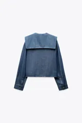 Camisa celeste de algodón con efecto denim, cuello bobo, escote pico, manga larga con puños y cierre frontal con botones.